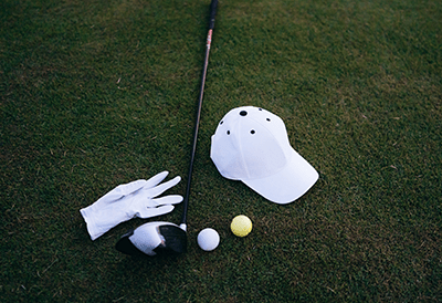 golf merchandise (hat, glove, club, and golf balls) on green