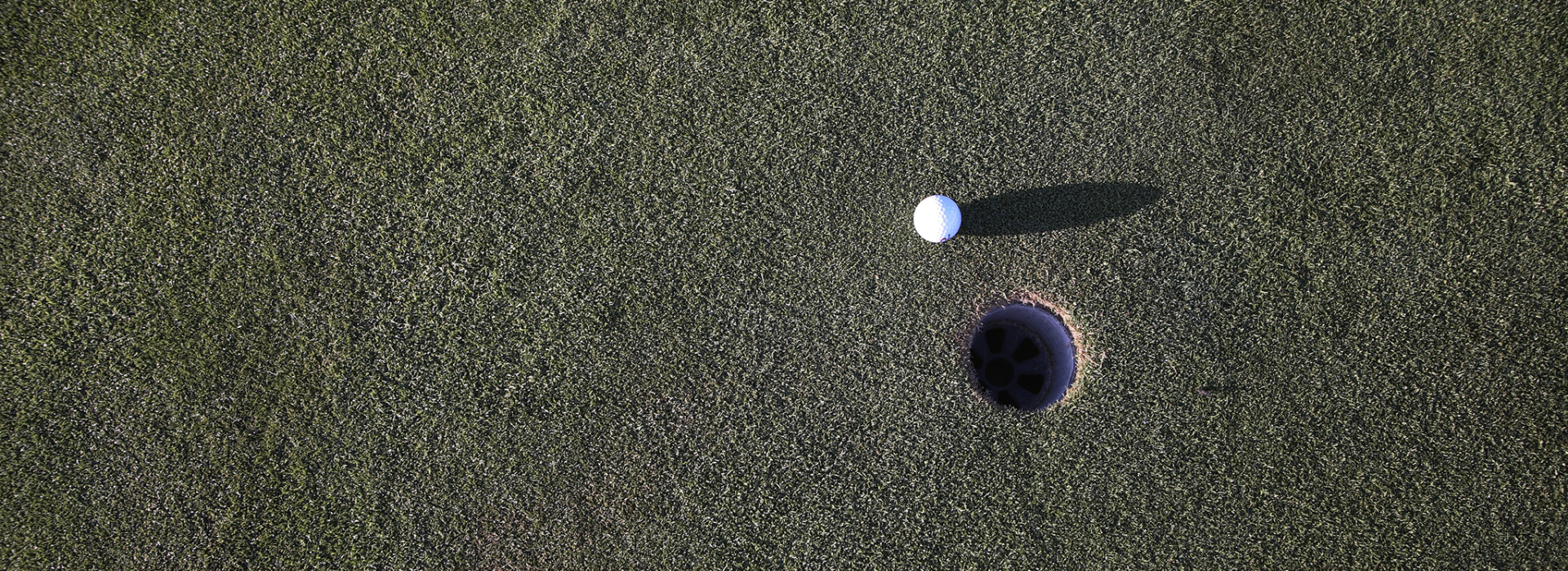 Golf ball next to hole aerial view